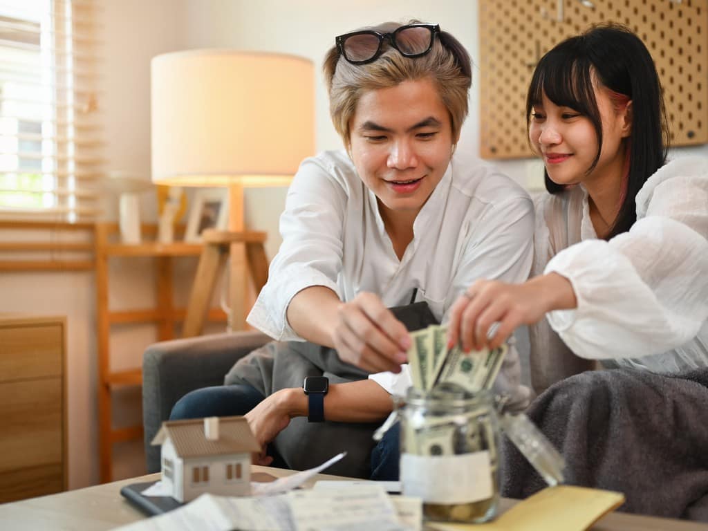 Buy condo in Pattaya มารีน่า โกลเด้น เบย์ : คอนโดหรูวิวทะเล ที่ให้คุณมากกว่าคำว่า "ที่อยู่อาศัย" 3 Buy condo in Pattaya happy young asian couple putting money into saving 2023 12 13 19 10 49 utc